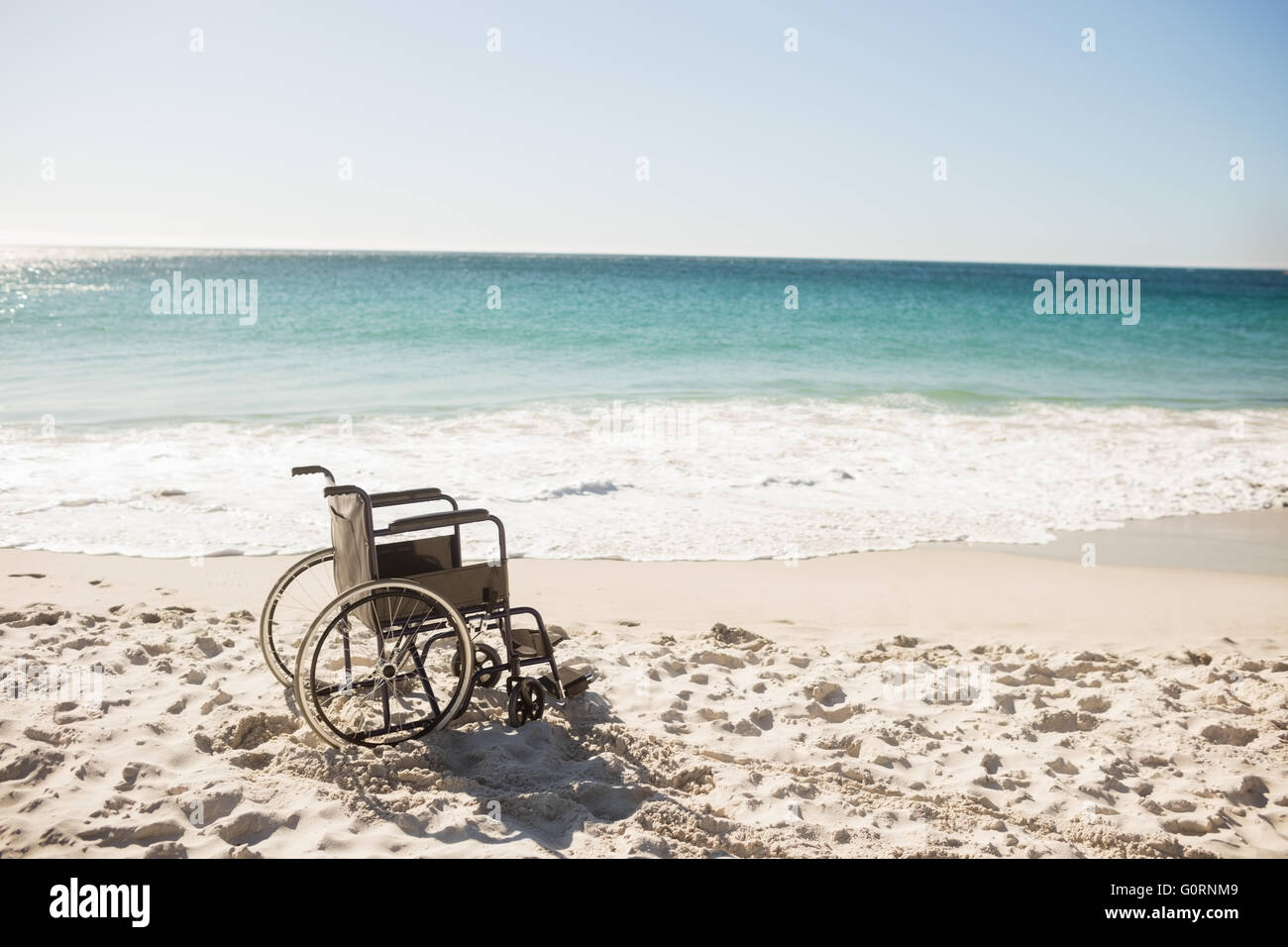 Sedia a rotelle nero sulla spiaggia Foto Stock