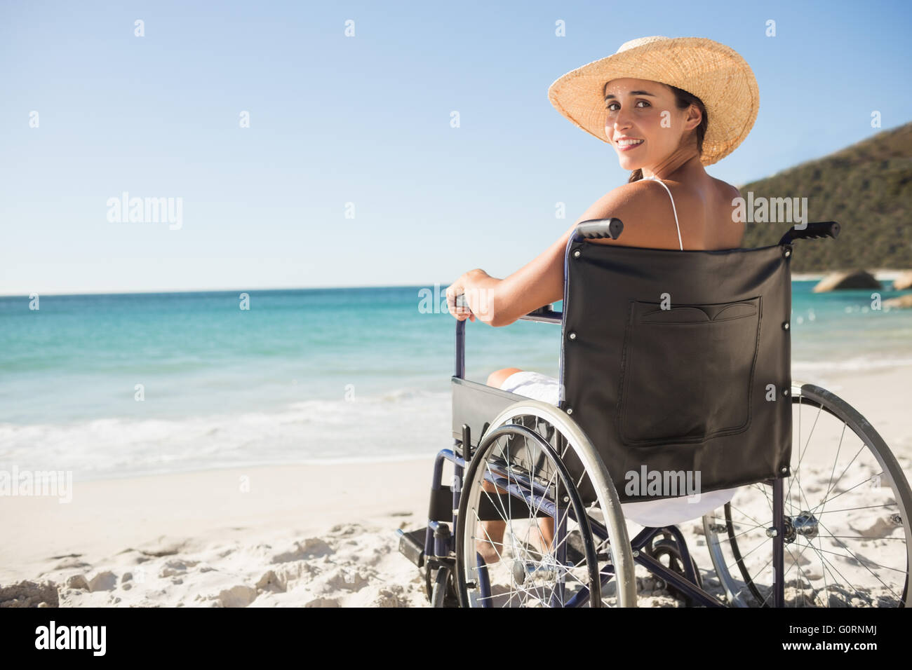 Sedia a rotelle donna seduta sorridente in telecamera Foto Stock