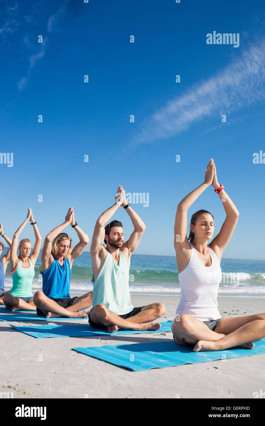 Persone che fanno lo yoga sulla spiaggia Foto Stock