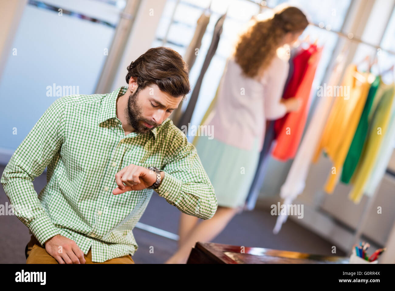 Annoiato uomo in attesa di sua moglie mentre la donna dal portabiti Foto Stock