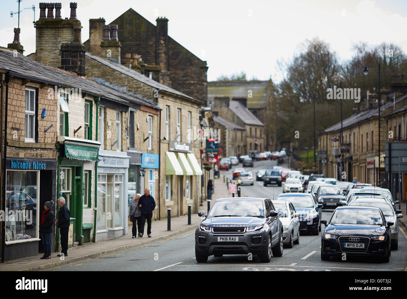 Rams fondo arte pubblica stemma Ramsbottom negozi di paese guardando giù Bolton Street pietra negozi terrazzate colline in backgro Foto Stock