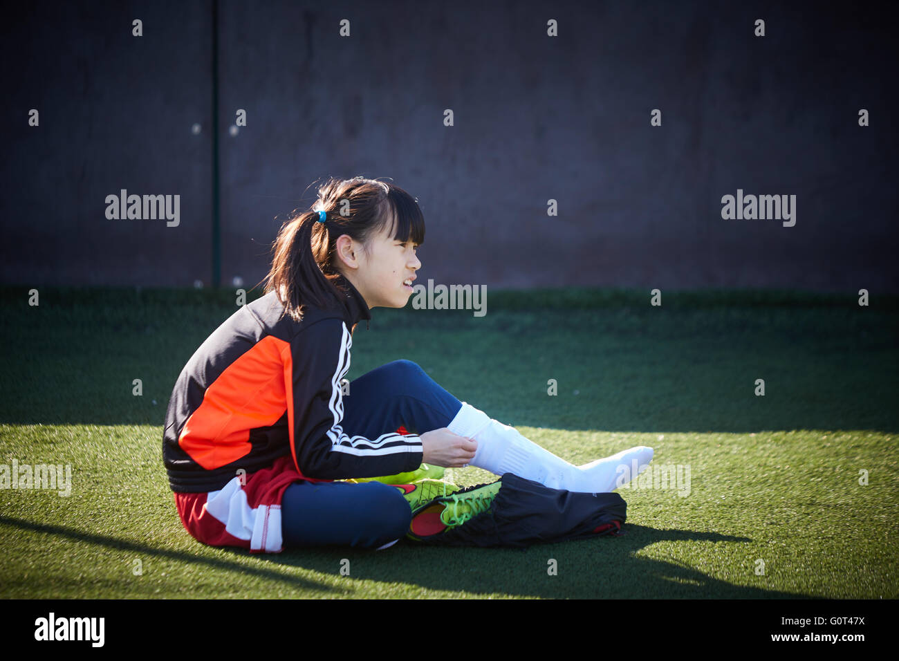 Cinese asiatica giovane calciatore Grill prepara la messa su scarpe stivali calza prima della partita copyspace Young kids bambini y Foto Stock