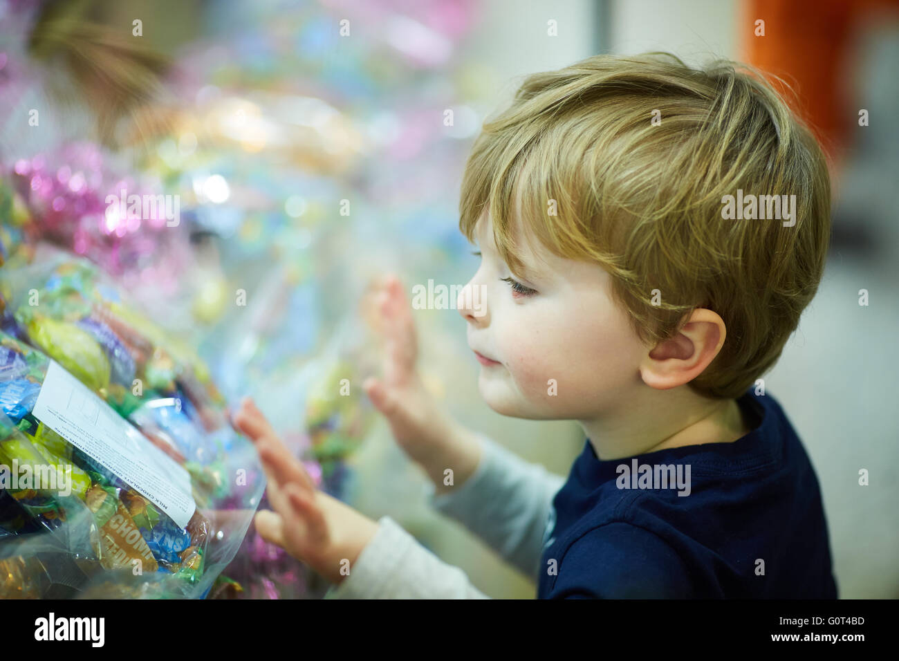 Piccolo Ragazzo guardando le caramelle attraverso un negozio visualizzazione finestra di zucchero salute cioccolatini che vogliono pocket denaro acquistando il compratore pester candy Foto Stock