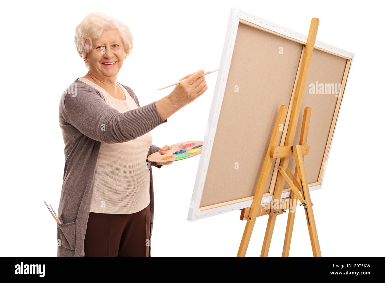 Senior lady dipinto su una tela di canapa e guardando la telecamera isolata su sfondo bianco Foto Stock