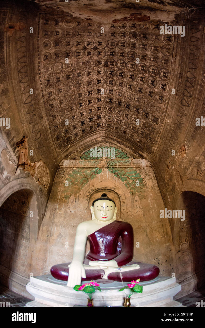 Tempio di Tayok Pye, statua del Buddha Bagan Myanmar // BAGAN, Myanmar - Una grande statua di Buddha con un profondo abito rosso si trova all'interno del santuario principale del Tempio di Tayok Pye, circondato da affreschi ben conservati che coprono le pareti e il soffitto della camera ad arco. Risalente al regno di re Narathihapate (1256-1287), il tempio di Tayok Pye si trova sul lato orientale della zona archeologica di Bagan vicino al villaggio di Minnanthu. Il tempio rappresenta la fase finale della costruzione monumentale prima che le invasioni mongole precipitassero il declino del regno pagano. La struttura è caratterizzata da intricati stucc rinnovati Foto Stock