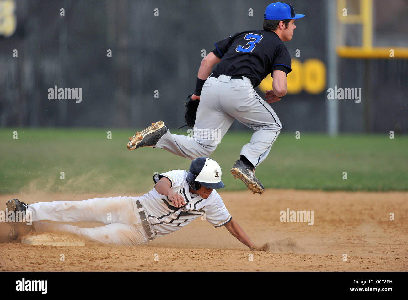 High school player scorrevole nel disco a seconda base nel tentativo di distruggere il relè su un doppio tentativo di riproduzione. Stati Uniti d'America. Foto Stock