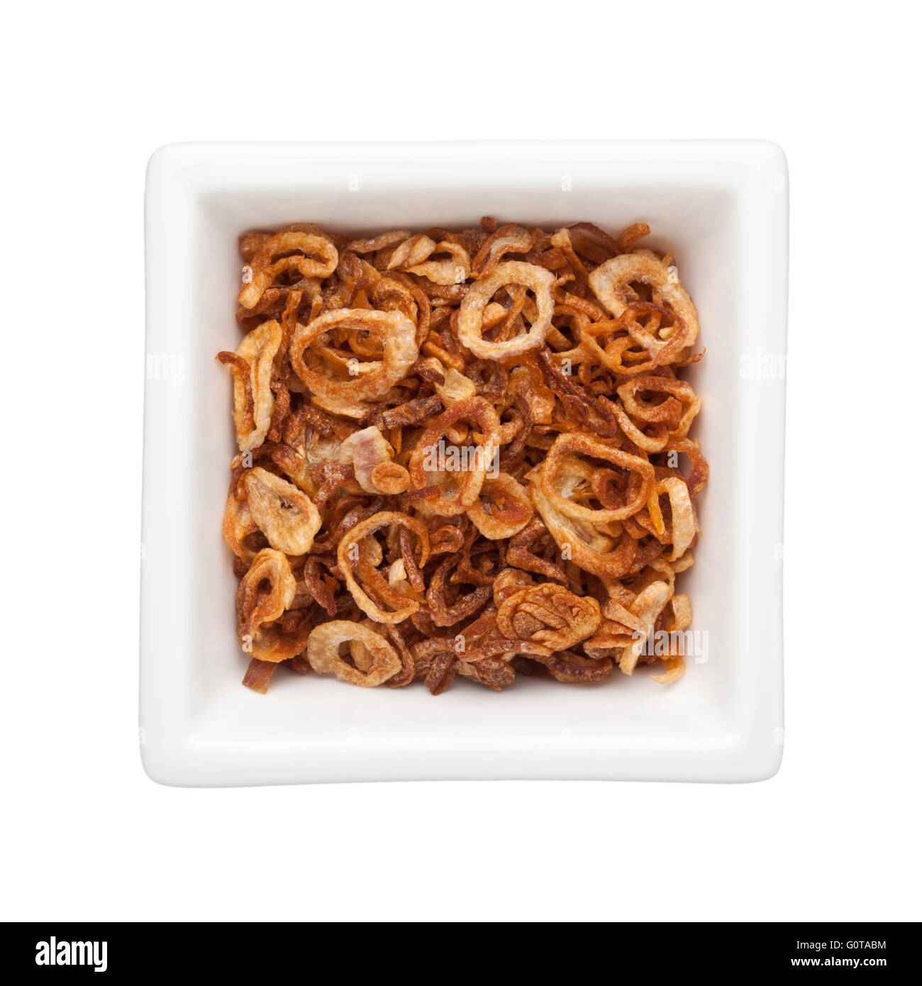 Fritti di scalogni tagliati a fette in un recipiente quadrato isolato su sfondo bianco Foto Stock
