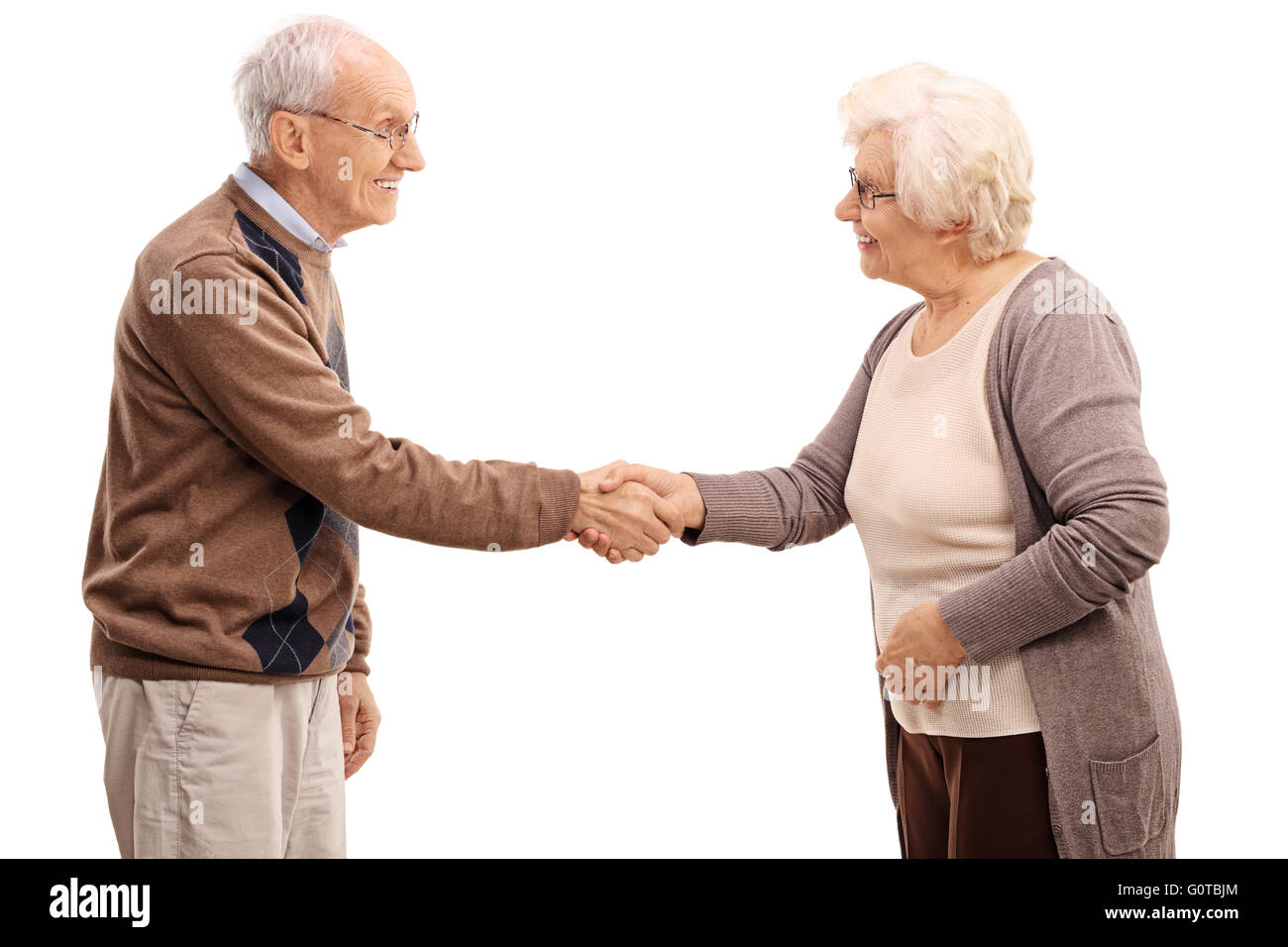 Anziani l uomo e la donna si stringono la mano e sorridente isolati su sfondo bianco Foto Stock