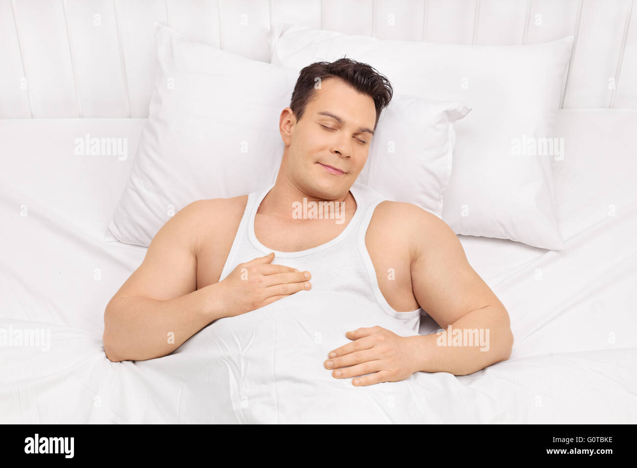 Felice giovane uomo di dormire su un letto comodo e sognare Foto Stock