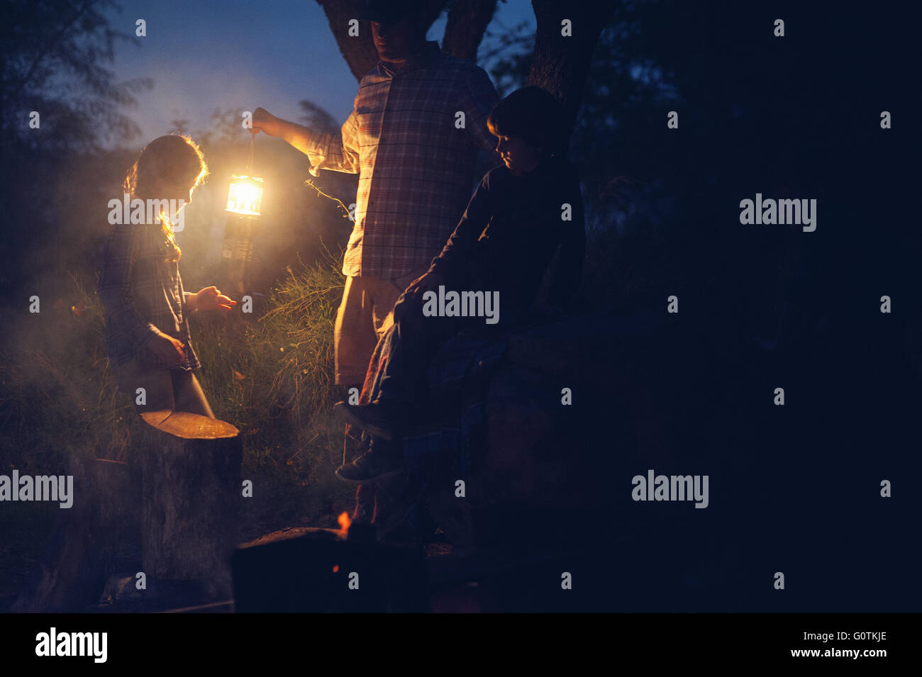 Uomo che tiene una lanterna mentre accampando con tre bambini, Texas, Stati Uniti Foto Stock