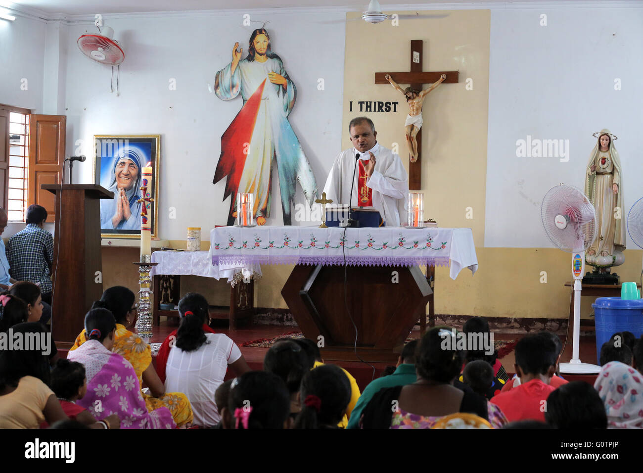 Sacerdote cattolico predica durante la messa domenicale nella piccola chiesa di Calcutta, in India Foto Stock