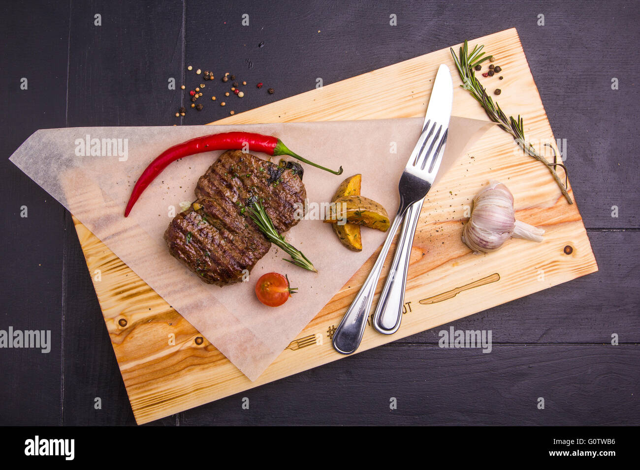 Concetto: cibo sano. In casa ai ferri Bistecca di vitello e le verdure su una tavola di legno con ingredienti e posate intorno Foto Stock