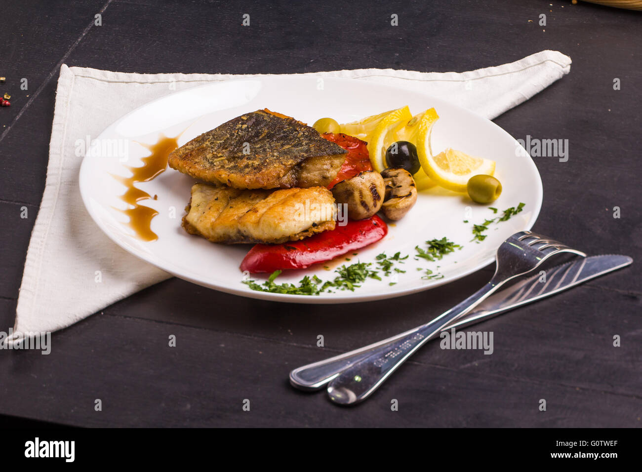 Concetto: cibo sano. In casa grigliate di pesce bistecca e le verdure su una piastra con ingredienti e posate intorno Foto Stock