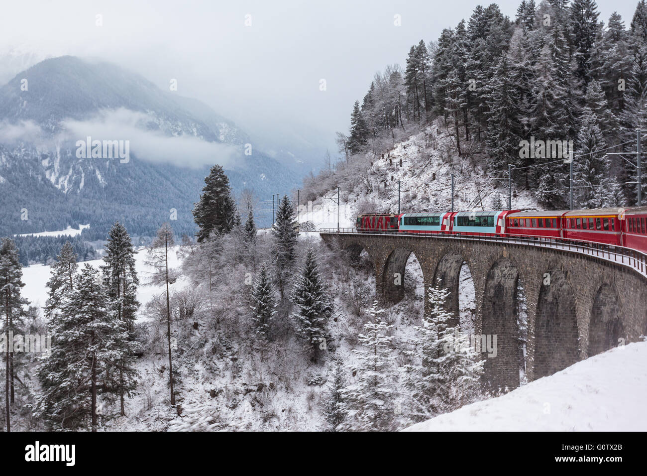 Famoso treno turistico in esecuzione oltre il viadotto in Svizzera, il Glacier Express in inverno Foto Stock