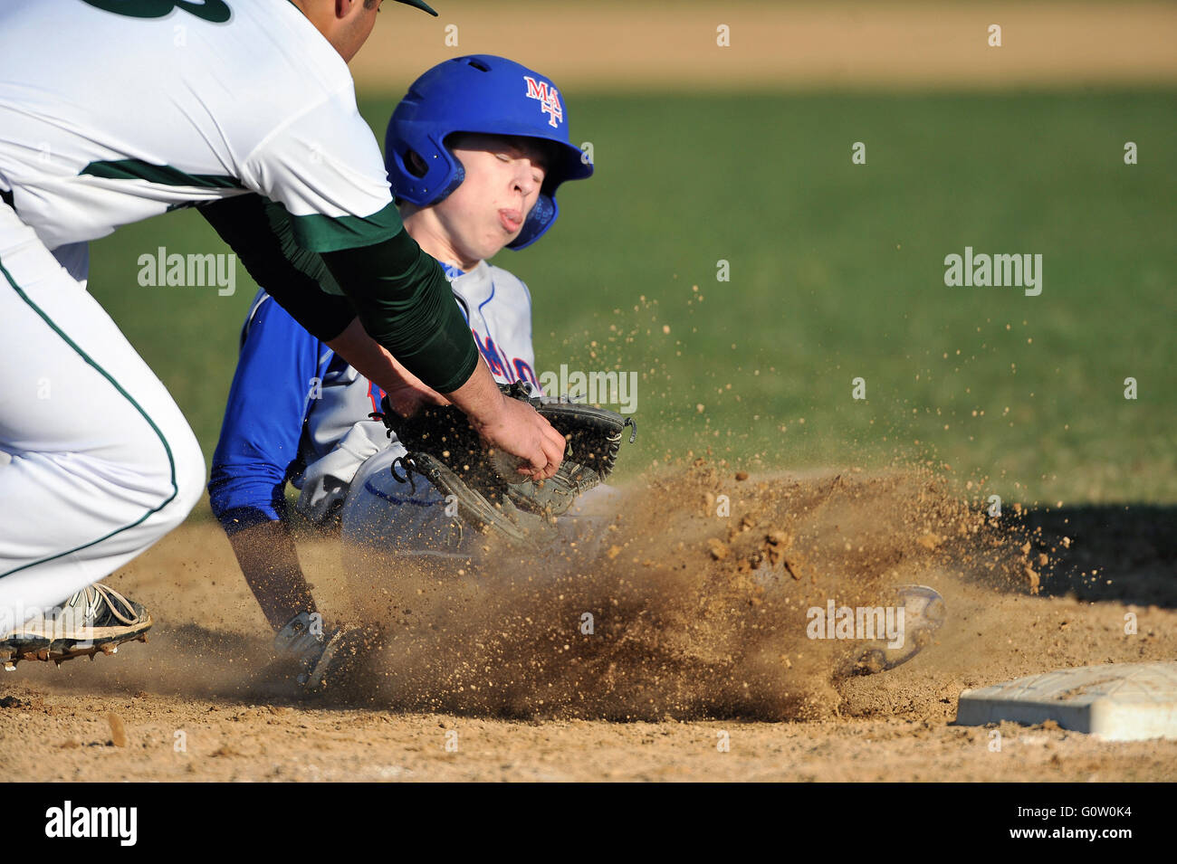 Un high school player scivolare in terza base come il terzo baseman applica un tag per il runner. Stati Uniti d'America. Foto Stock