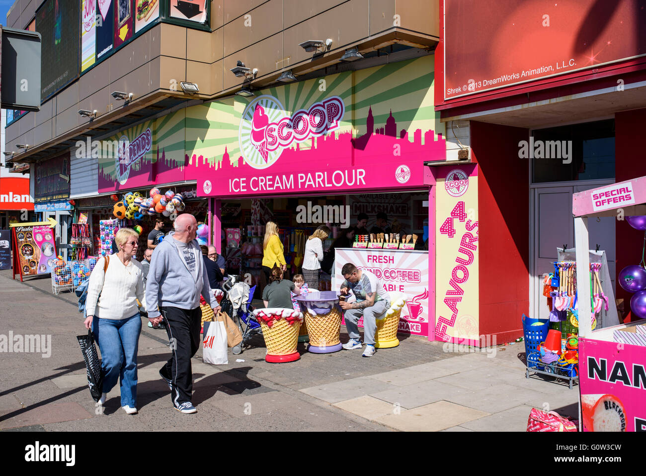 Un giovane a piedi passato persone godendo di gelato presso il convogliatore gelateria sul lungomare di Blackpool, Lancashire, Regno Unito Foto Stock