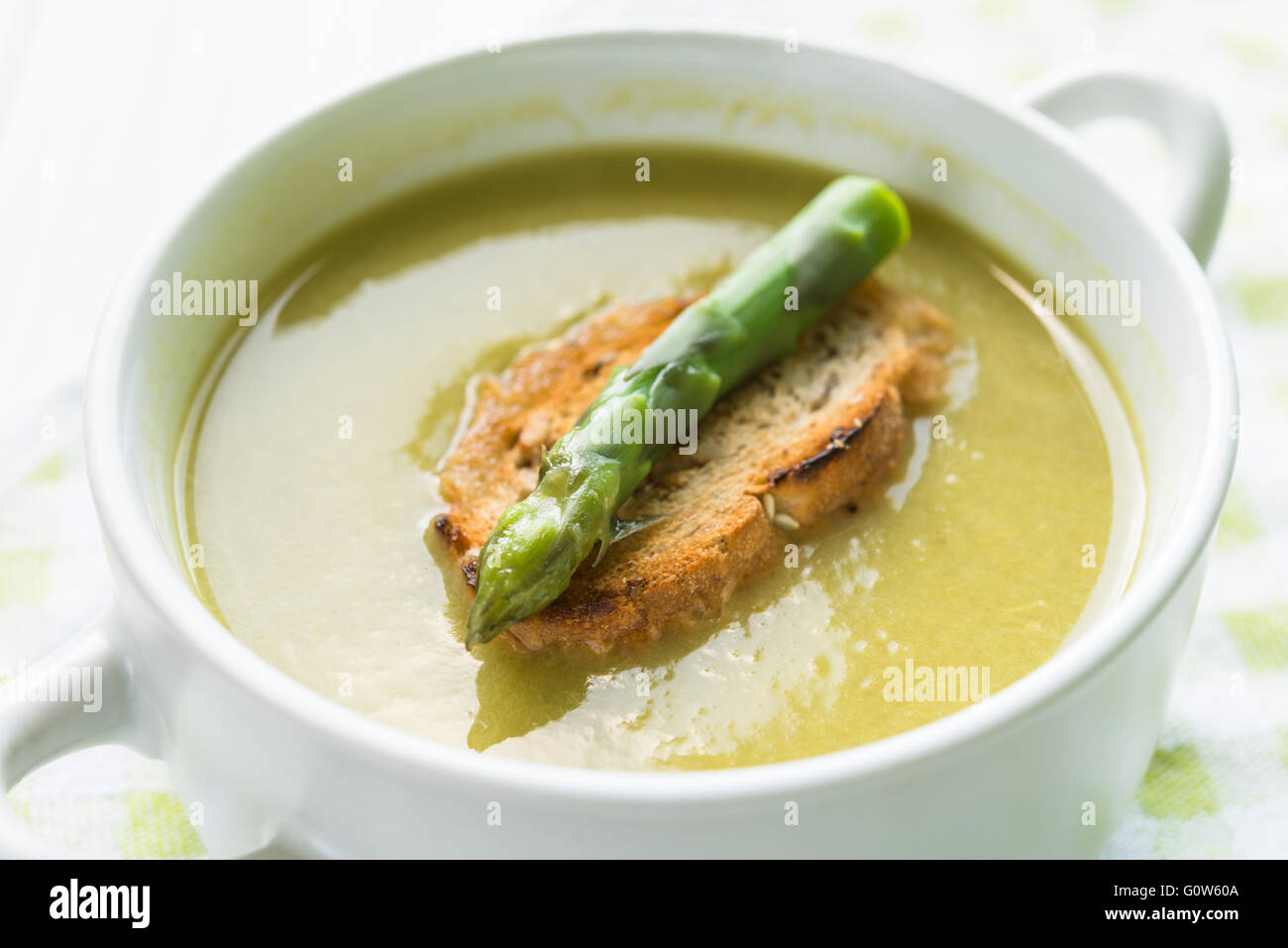 Primo piano della zuppa di asparagi in una ciotola bianca con la fetta di pane e asparagi lancia sulla parte superiore Foto Stock