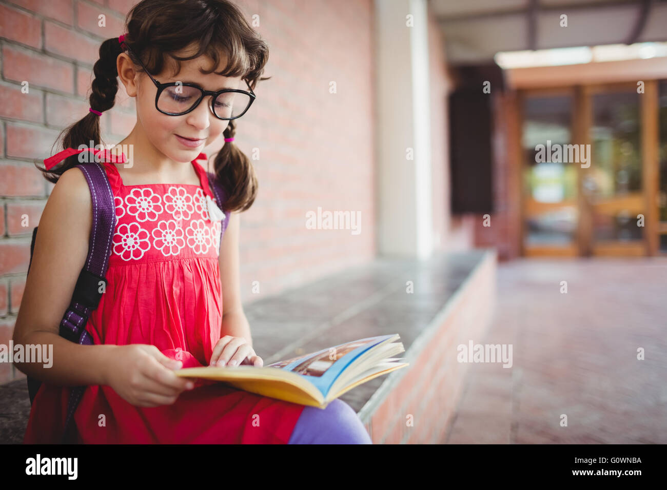 Seduto schoolgirl la lettura di un libro Foto Stock
