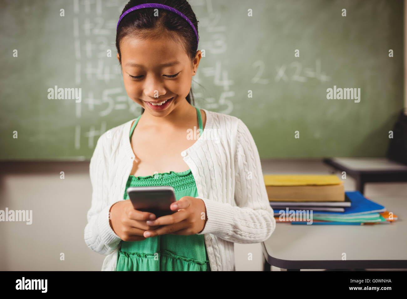 Schoolgirl sorridente mentre si tiene lo smartphone Foto Stock