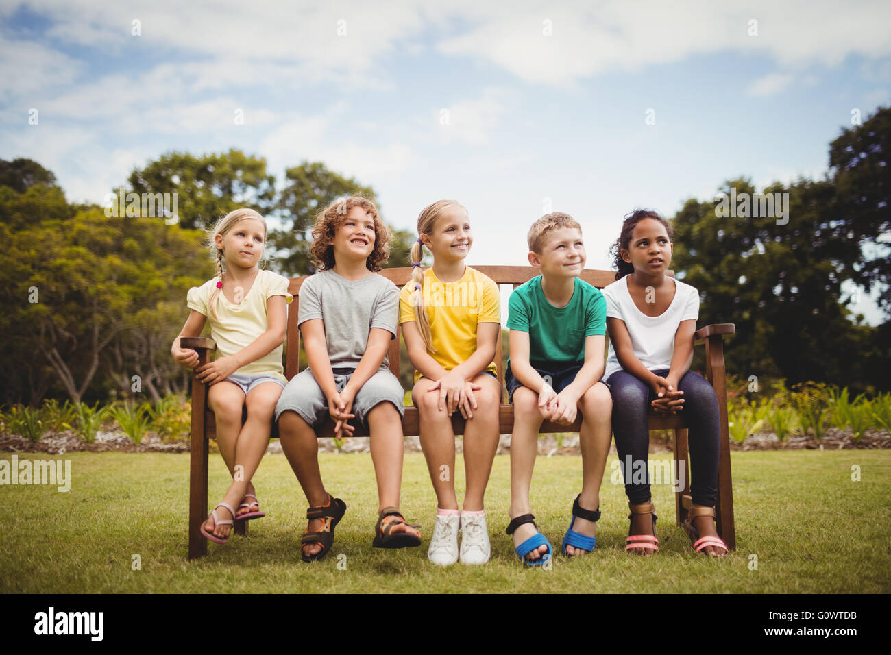 Dei bambini felici seduta su una panchina Foto Stock