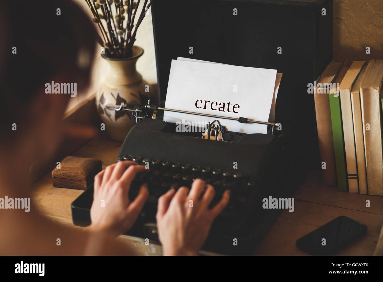 Creare contro la giovane donna utilizzando una macchina da scrivere Foto Stock