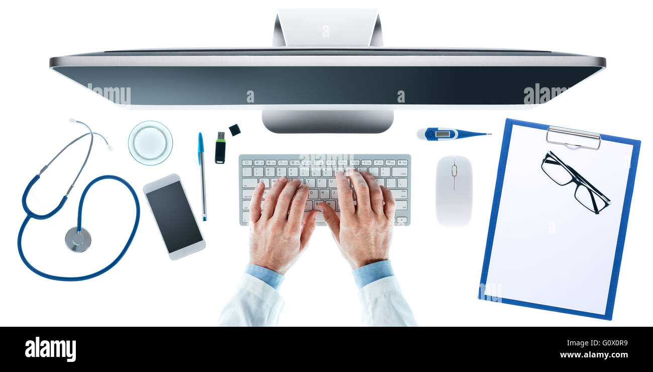 Medico al banco lavorando al computer con attrezzature mediche su sfondo bianco e con le mani vicino, vista dall'alto Foto Stock