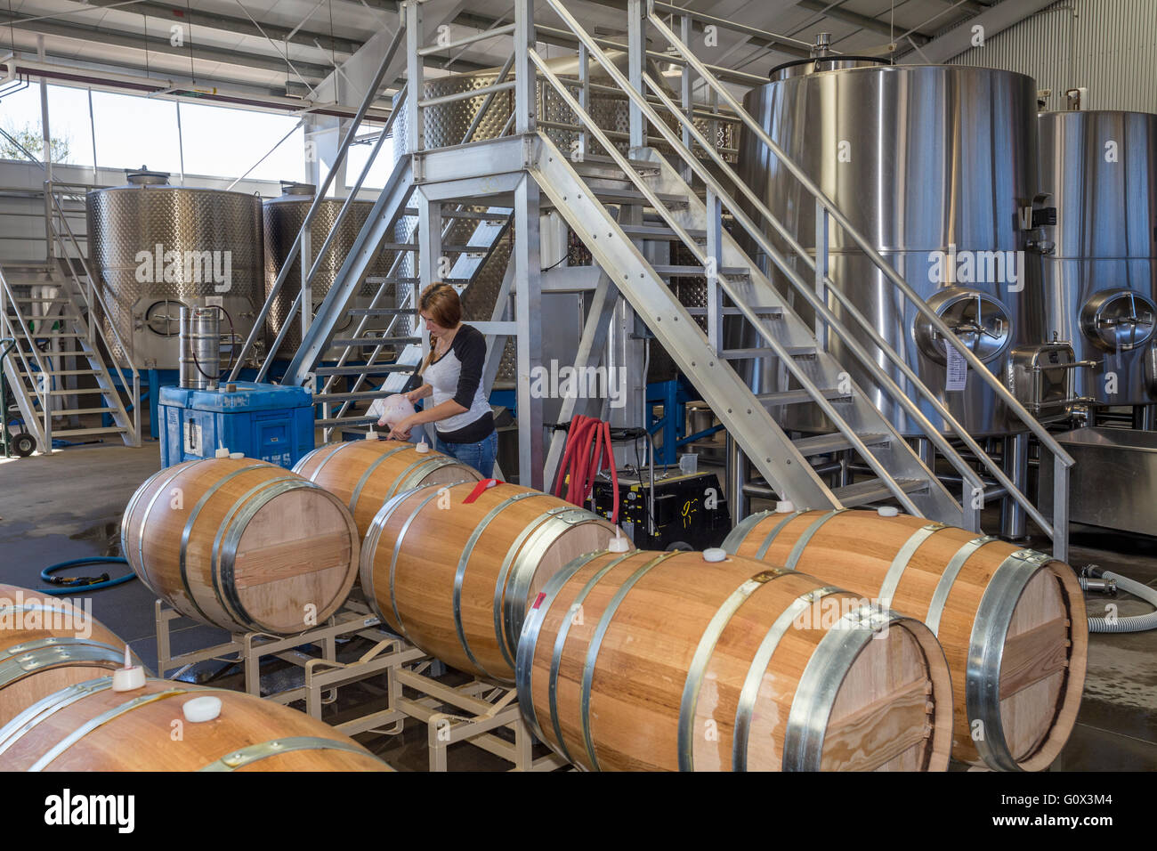 Lavoratore rabbocco di botte di vino nella zona di fermentazione al rammendo cantina di parete lungo silverado trail nella valle di Napa California Foto Stock