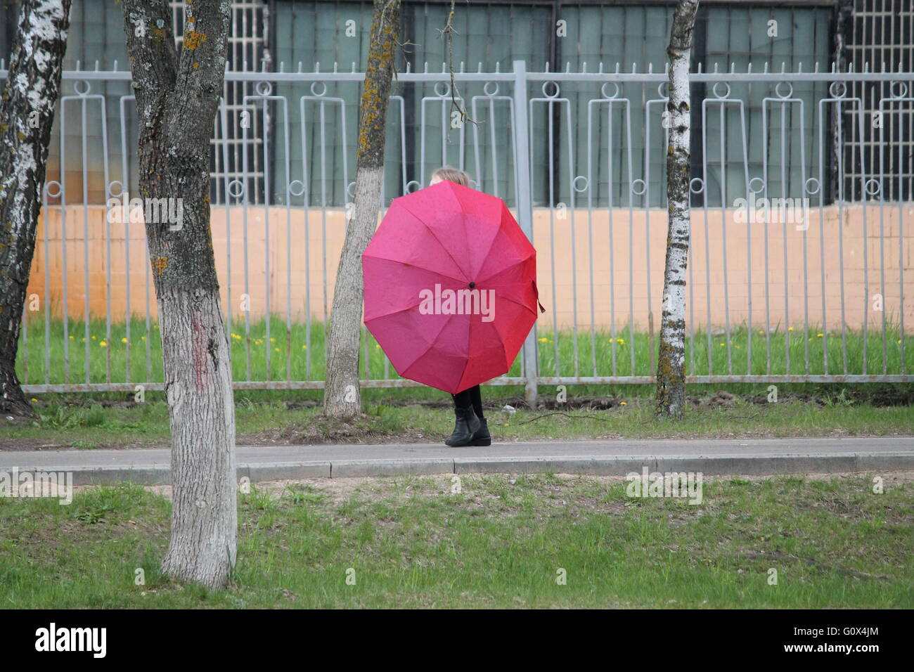 Bellissima bambina gioca con ombrello rosa in primavera piovosa giornata Foto Stock