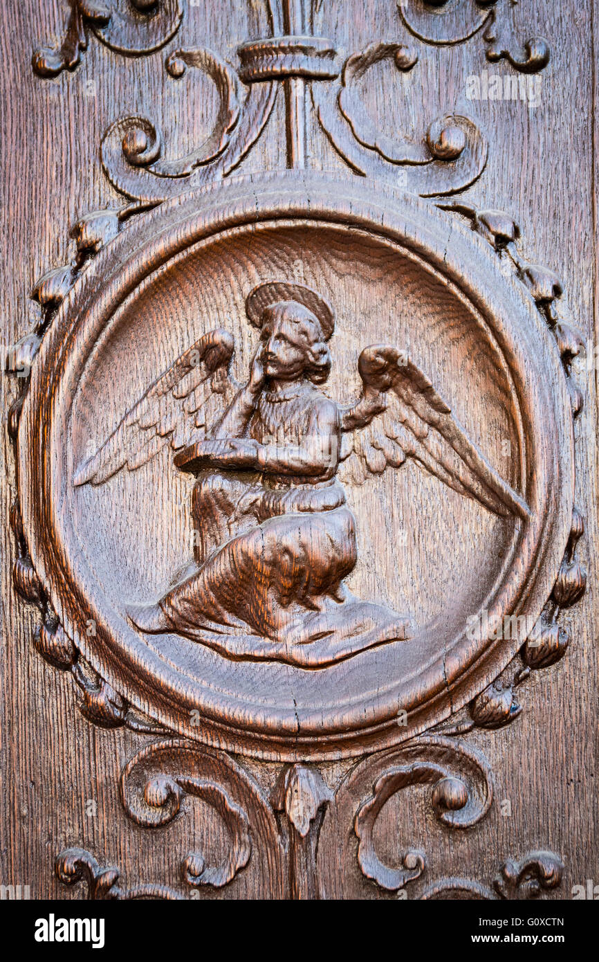 Angelo inciso sul portale in legno di una chiesa medievale. Foto Stock