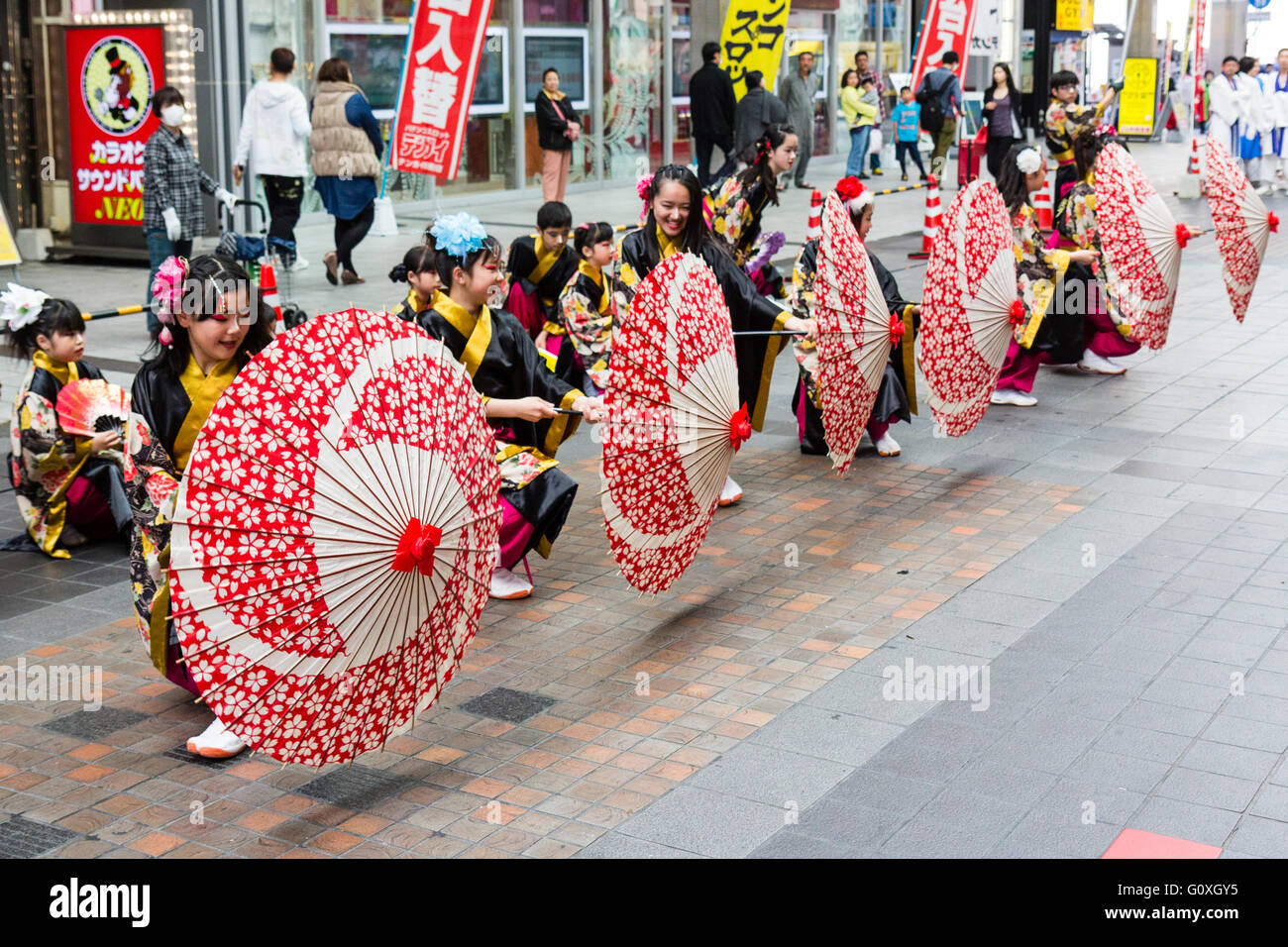 Yosakoi giapponese festival. Fila di bambini, in nero yukata, in ginocchio  e del moto vorticoso ombrelli bianchi e rossi, mentre si esegue la danza  nella galleria di negozi Foto stock - Alamy
