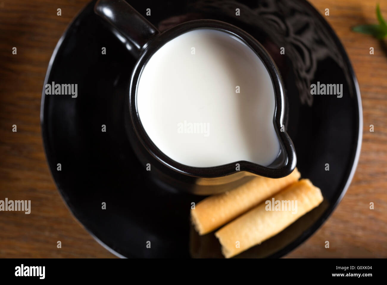 Tazza di latte con il mais dolce rotoli sulla piastra con sfondo di legno Foto Stock
