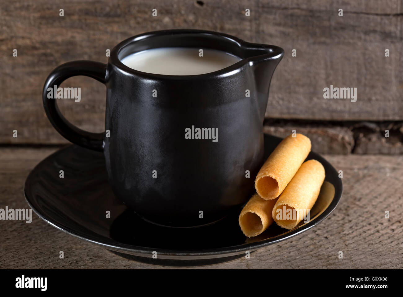 Tazza di latte con il mais dolce rotoli sulla piastra con sfondo di legno Foto Stock