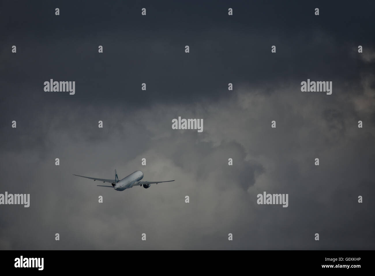 Un Cathay Pacific di velivoli a getto si arrampica in nuvole temporalesche dopo il decollo da Sydney Foto Stock