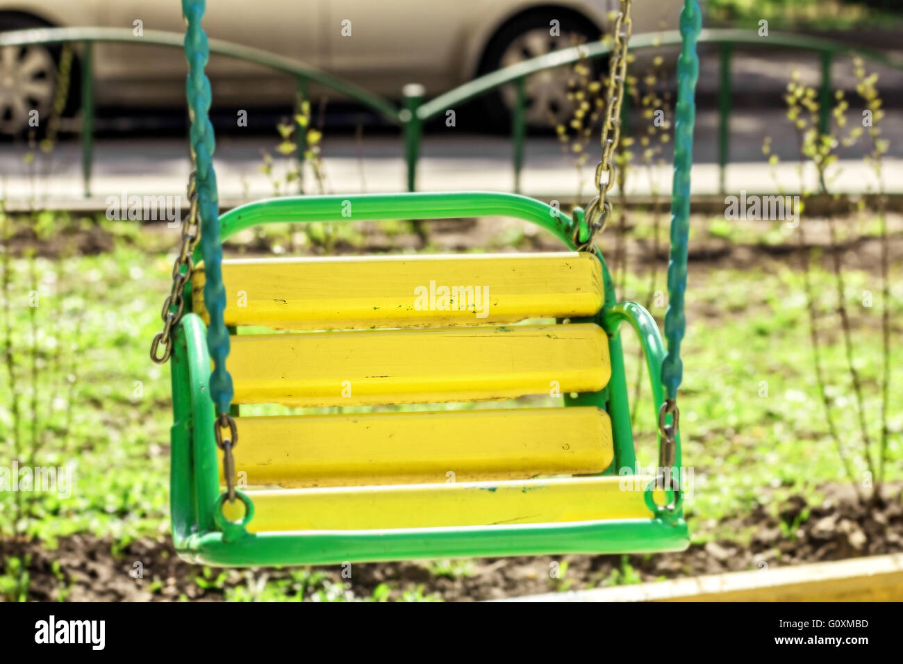 Bambino in legno swing giallo soleggiata giornata di primavera Foto Stock