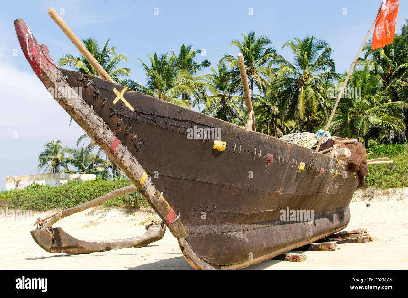 La barca di legno si erge sul bordo della spiaggia. La barca di legno su macchie di fondo. Vista delle barche sullo sfondo delle palme Foto Stock