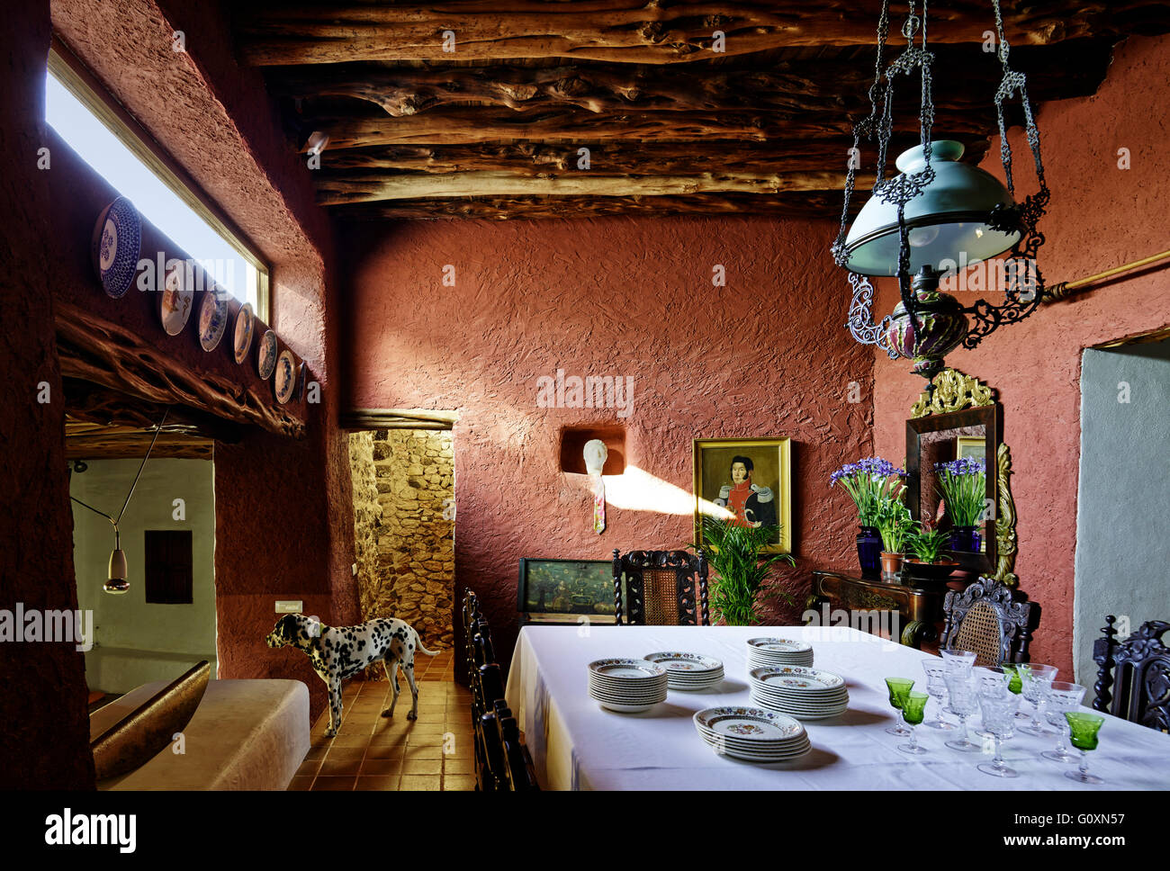Country House, Ibiza. In una villa sala da pranzo spazio con pareti rosso. Un cane dalmata. Tabella con un panno bianco e la Cina. Foto Stock