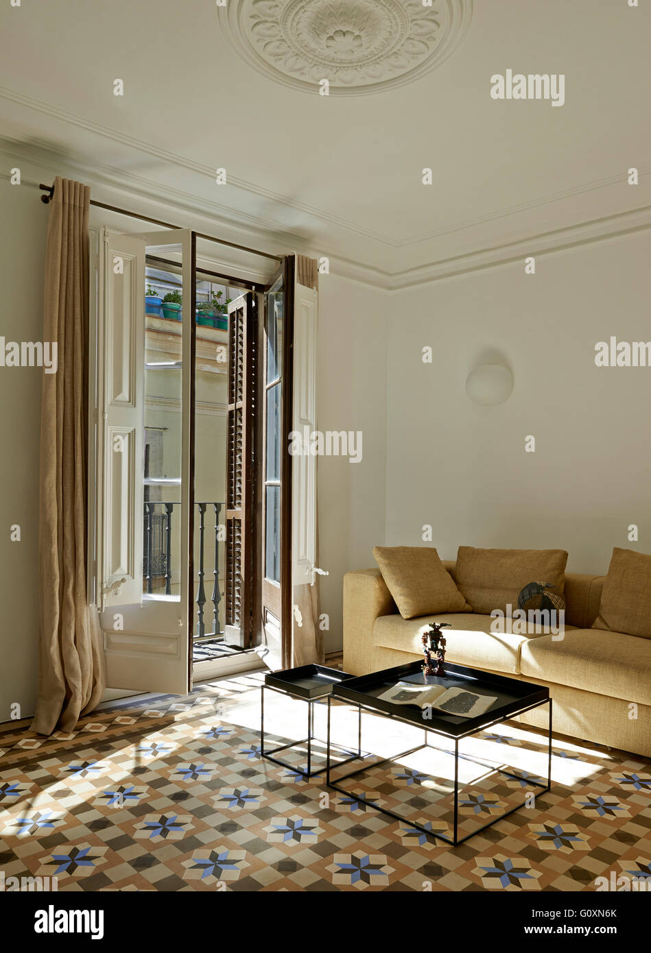 Appartamento Cervantes, Barcelona, Spagna. Soggiorno con divano e tavolo e  una ceramica pavimento a motivi geometrici. Lunghe finestre da pavimento a  soffitto Foto stock - Alamy