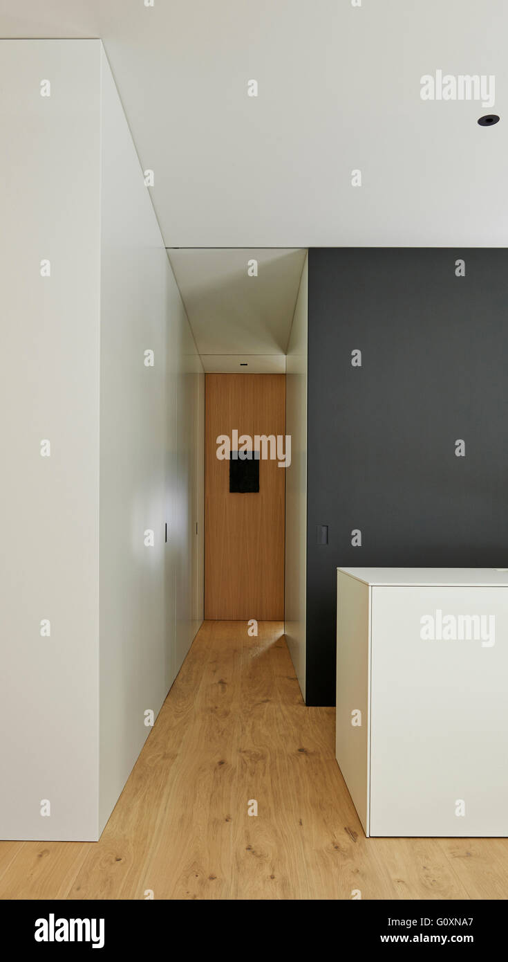 Stretto corridoio moderno con pavimenti in legno e in bianco e nero e pareti bianche. Foto Stock