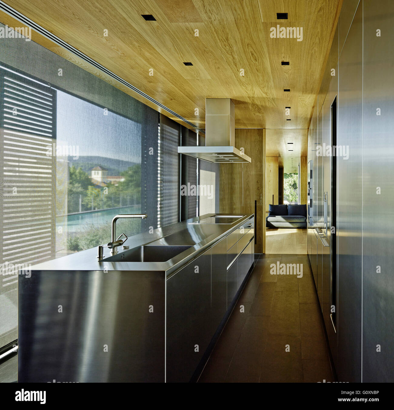 Restringere la cucina moderna con acciaio inossidabile stazione di lavoro e pavimenti in legno. Finestre da pavimento a soffitto. Foto Stock