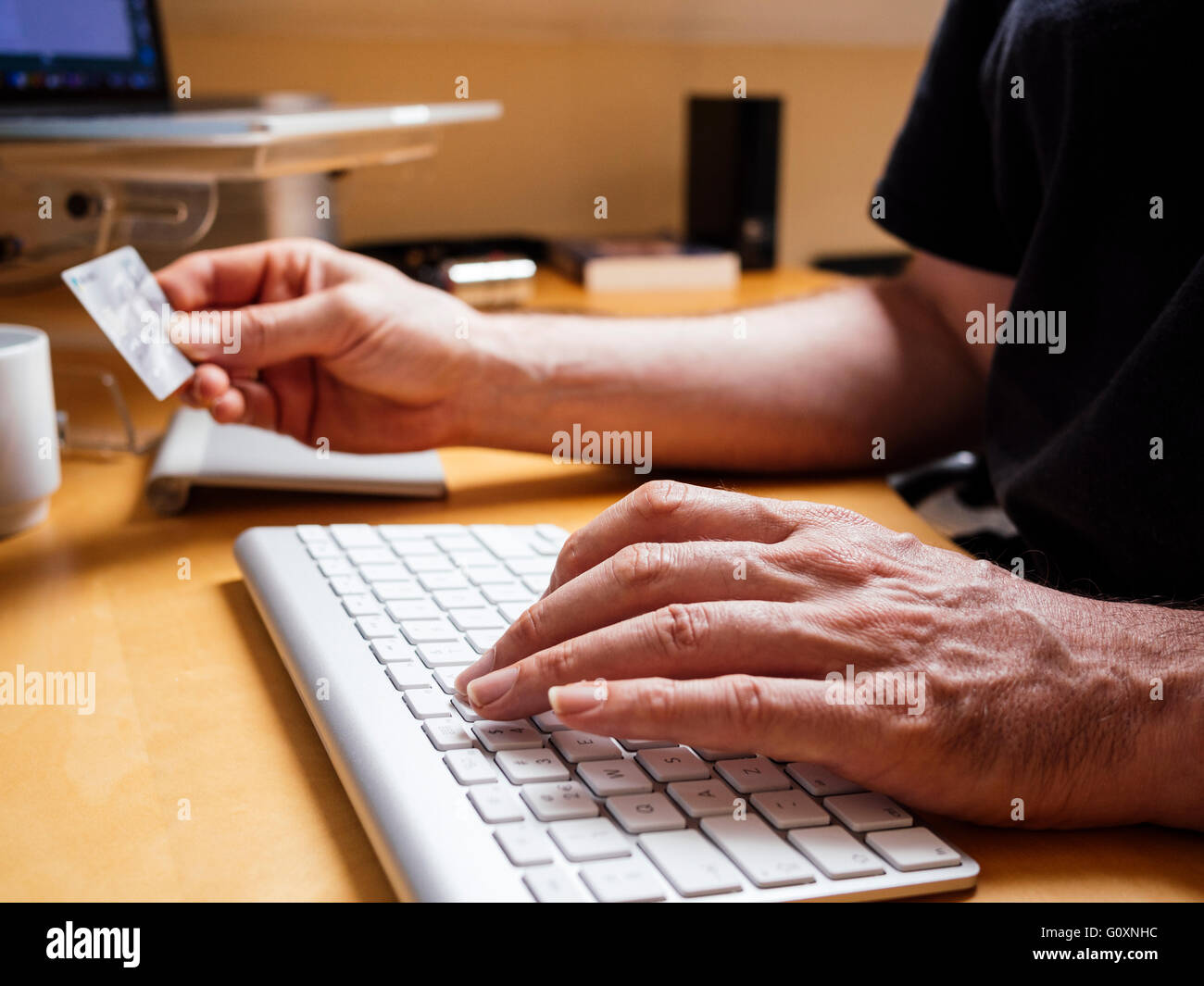 L'uomo immettendo il numero della carta di credito sulla tastiera di un computer. Foto Stock
