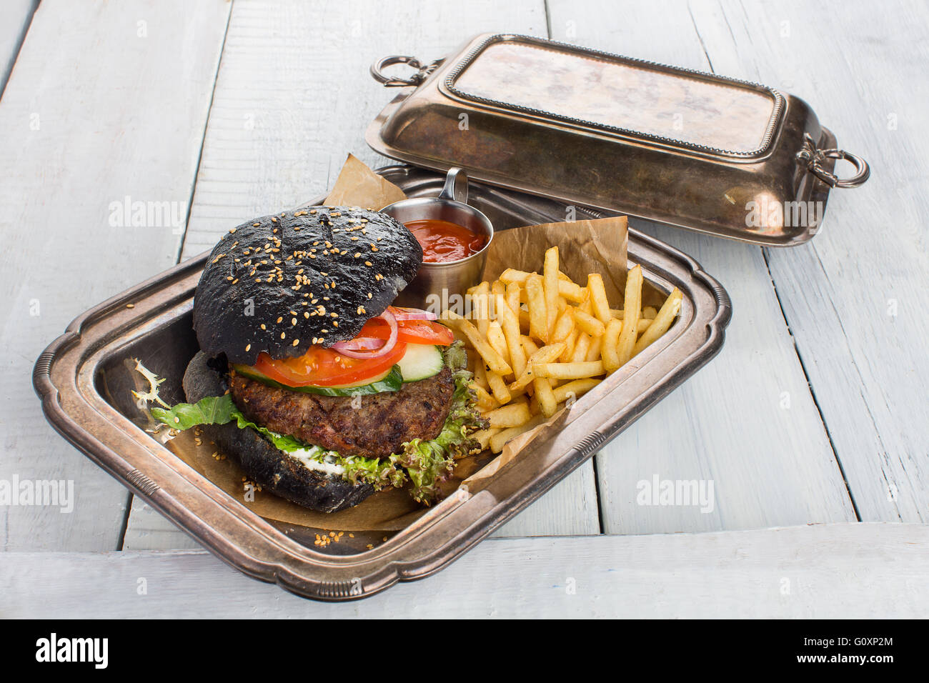Burger di nero su carta craft, bianco tavola di legno Foto Stock