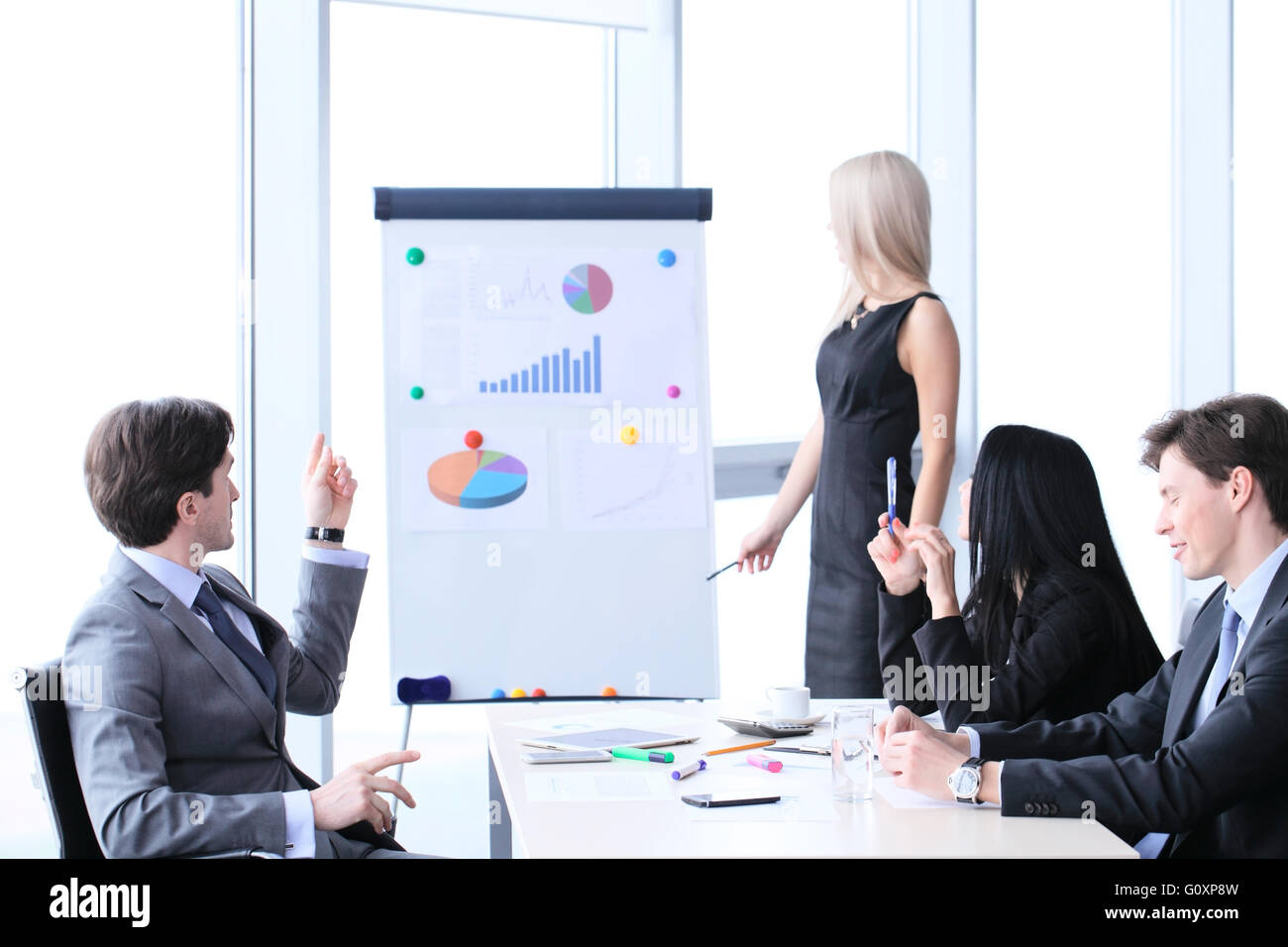 Lavoratori a business meeting guardando alla presentazione di relazioni finanziarie in un ufficio moderno Foto Stock