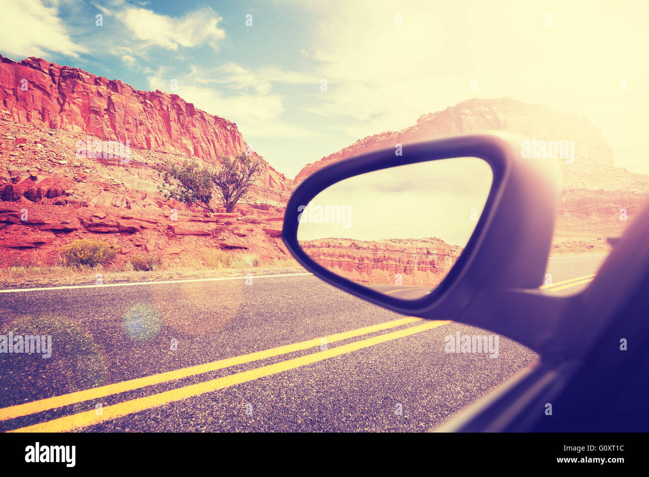 Vintage auto stilizzata ala specchio con lente effetto flare, concentrarsi sulle montagne, il concetto di viaggio. Foto Stock