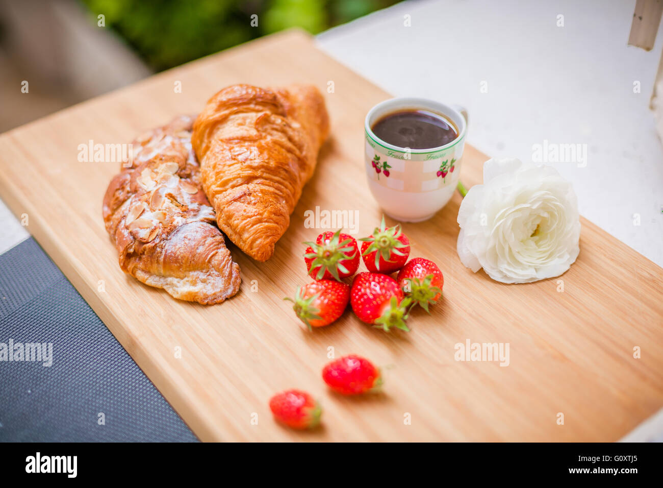 Morbido croissant francesi con bacche, una tazza di caffè e fiori freschi. Messa a fuoco selettiva. Foto Stock