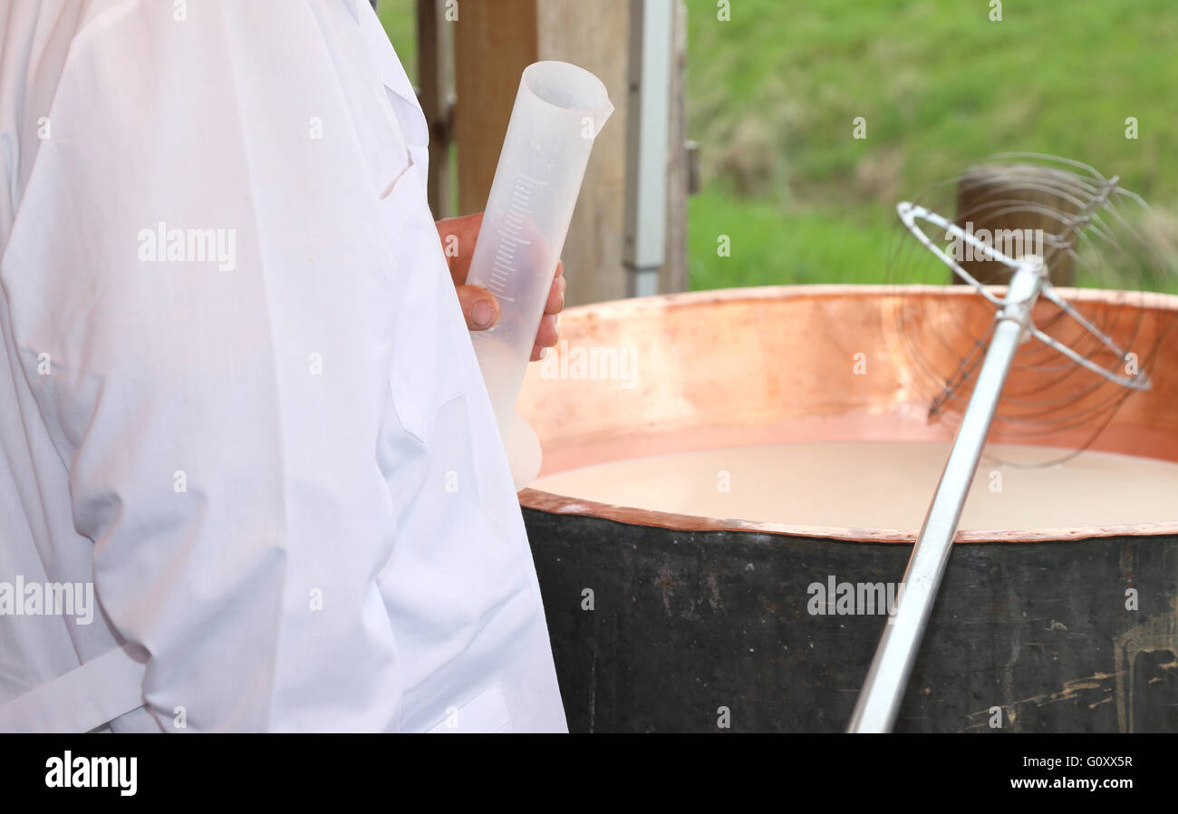Casaro con camici e tubo di plastica per versare il caglio al latte Foto Stock