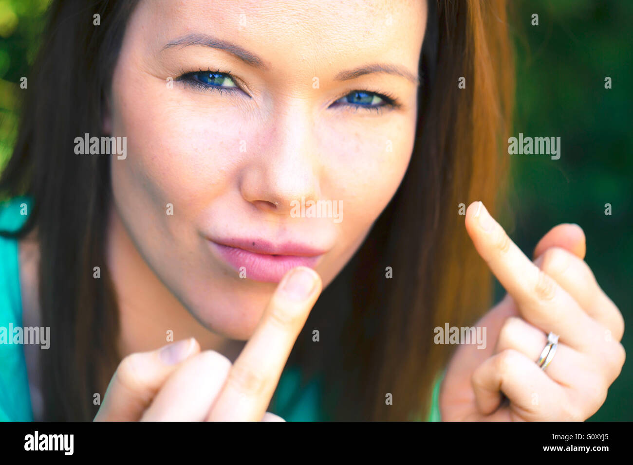 Ritratto di una donna al di fuori dando rude con il dito guardando la telecamera Foto Stock