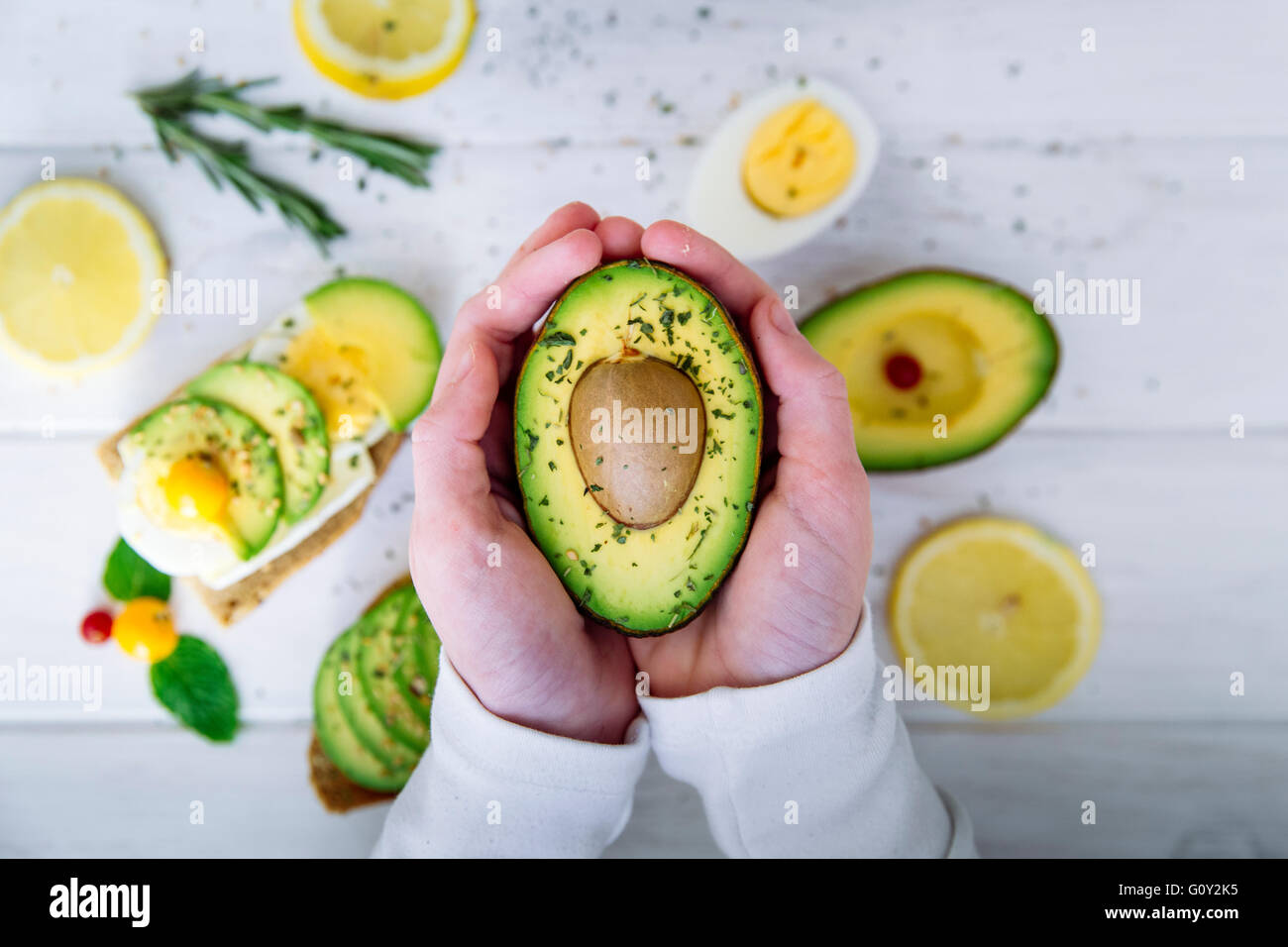 Mani tenendo la metà di un frutto di Avocado Foto Stock