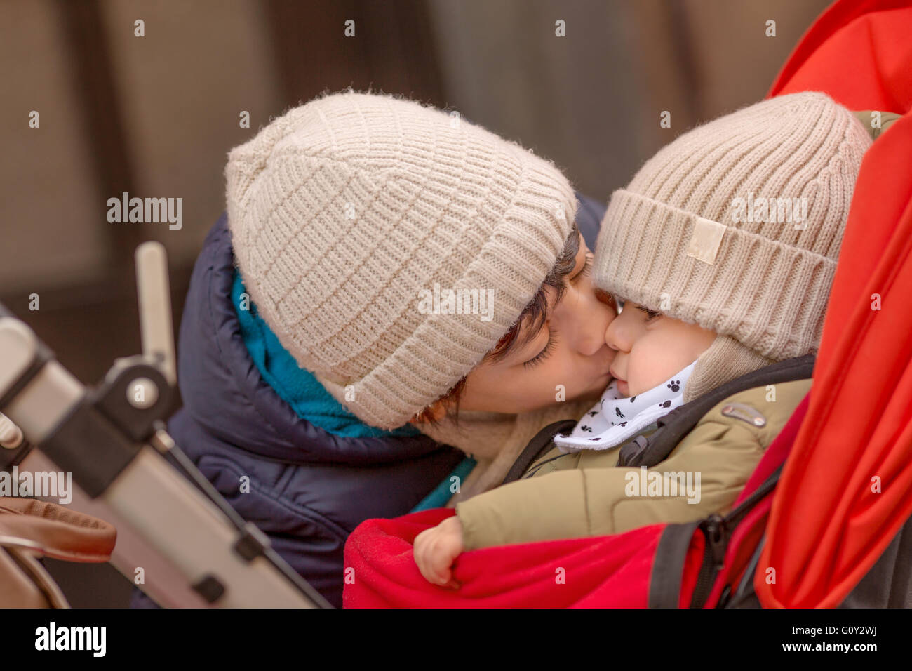 Ragazzo baciare il fratello del bambino nel passeggino Foto Stock