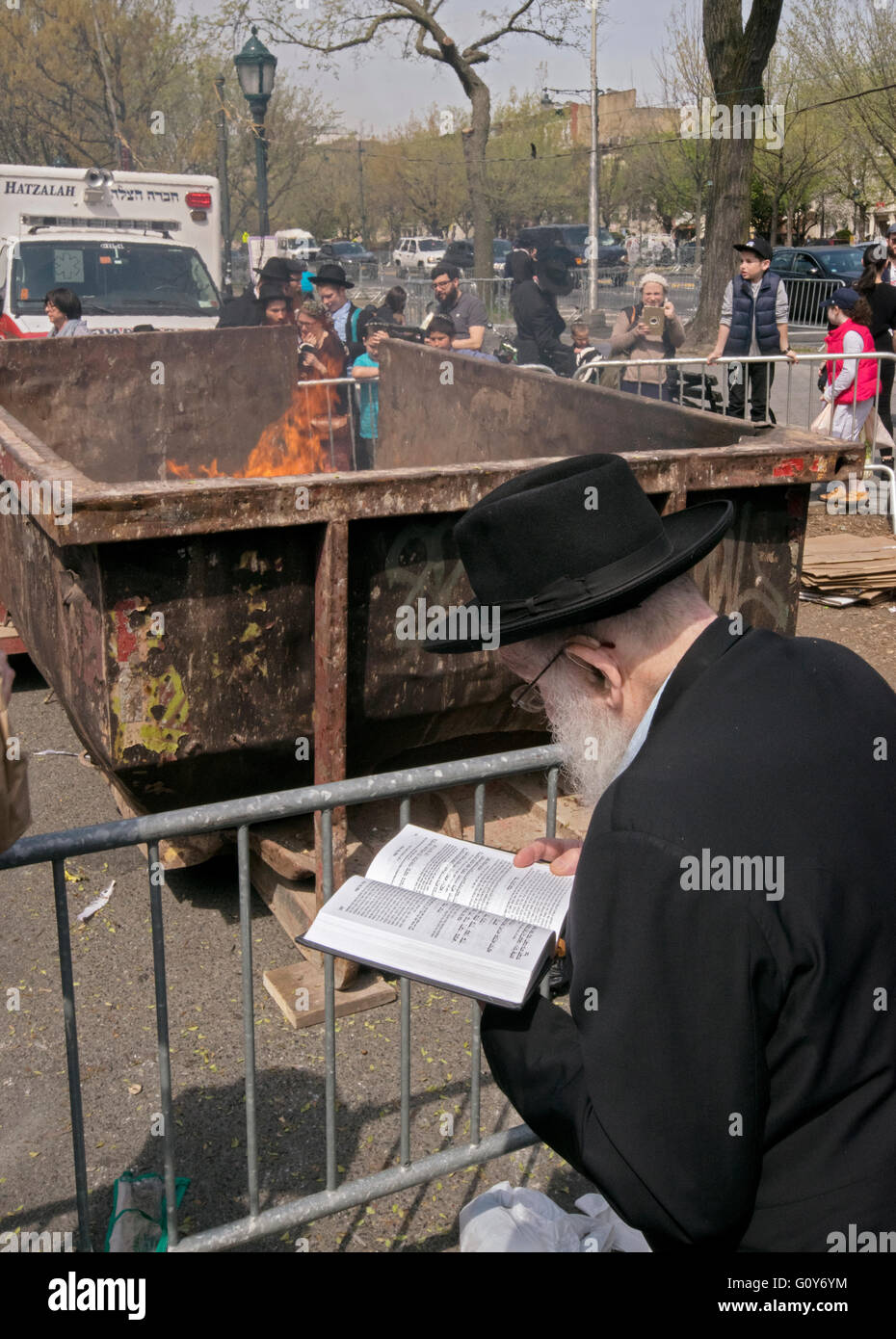 Una religiosa ebraica uomo la lettura di una preghiera dopo la masterizzazione il suo pane prodotti il giorno prima della Pasqua ebraica. In Brooklyn, New York. Foto Stock