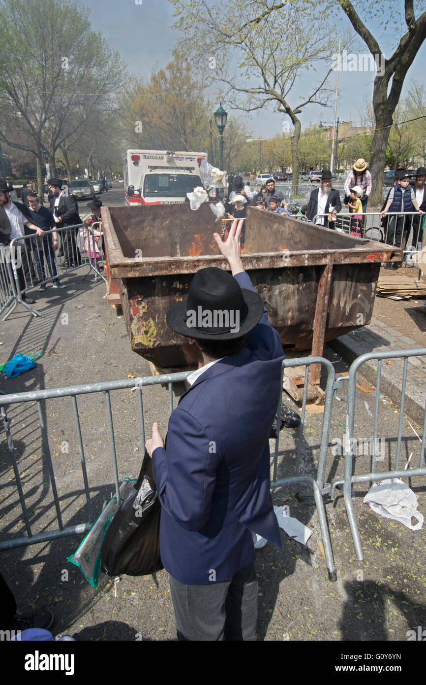 Una religiosa ebraica uomo gettare i prodotti di pane in un falò il giorno prima della Pasqua ebraica. In Brooklyn, New York. Foto Stock